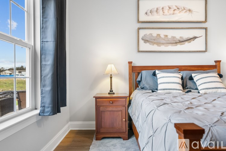 A bedroom with a bed, nightstand, and two framed pictures on the wall.