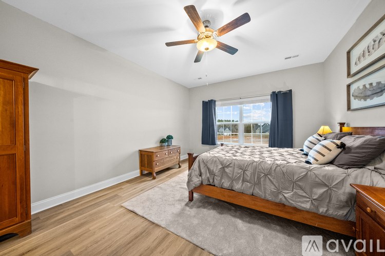 A bedroom with a bed, dresser, and ceiling fan.