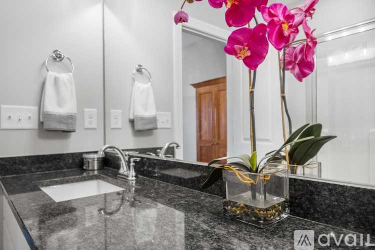 A bathroom with a sink, mirror, and a vase of flowers.