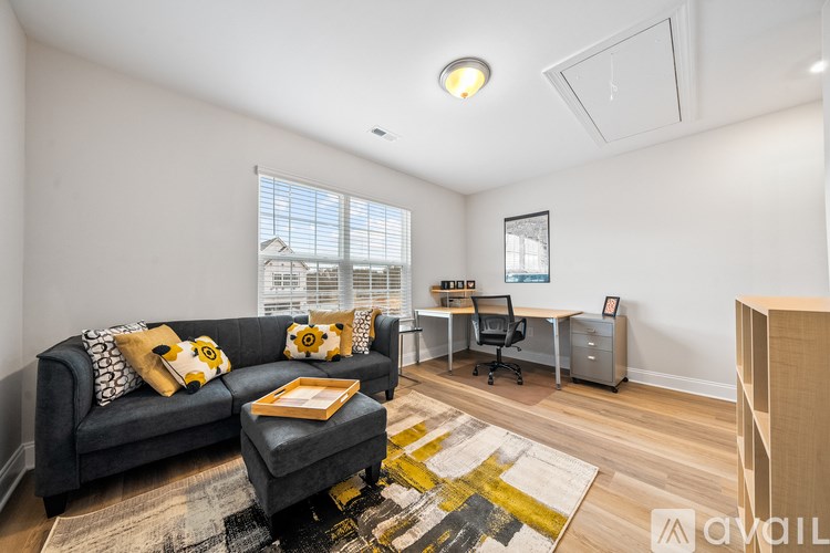 A living room with a grey couch and a yellow and black rug.