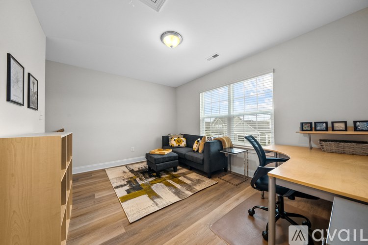 A living room with a black couch, a wooden desk, and a rug.