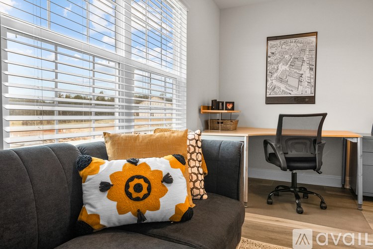 A living room with a grey couch, a black chair, and a framed picture on the wall.