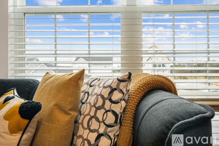 A couch with a yellow pillow and a grey cushion is in front of a window.