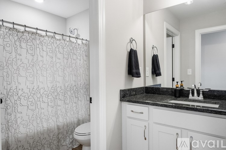 A bathroom with a patterned shower curtain and a sink with a mirror above it.