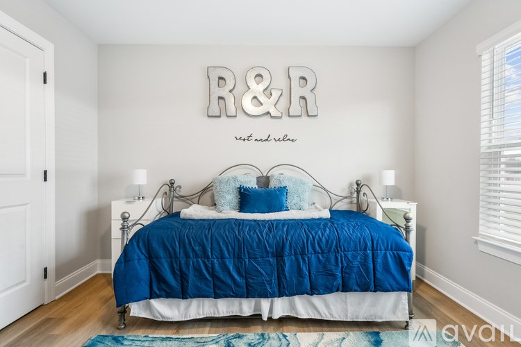 A bedroom with a bed and a wall decoration that reads "R&R".