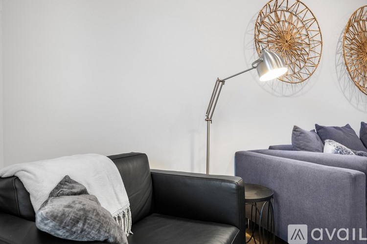 A black leather couch with a grey blanket and a grey sofa with a pillow.