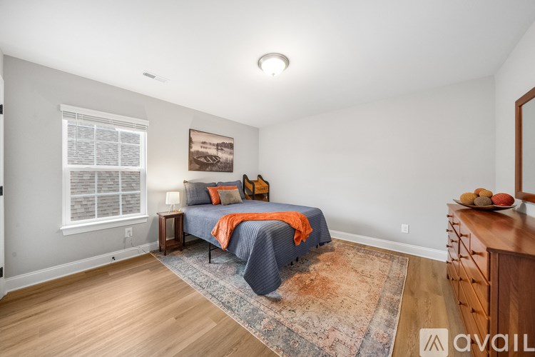 A bedroom with a bed, a rug, and a wooden dresser.
