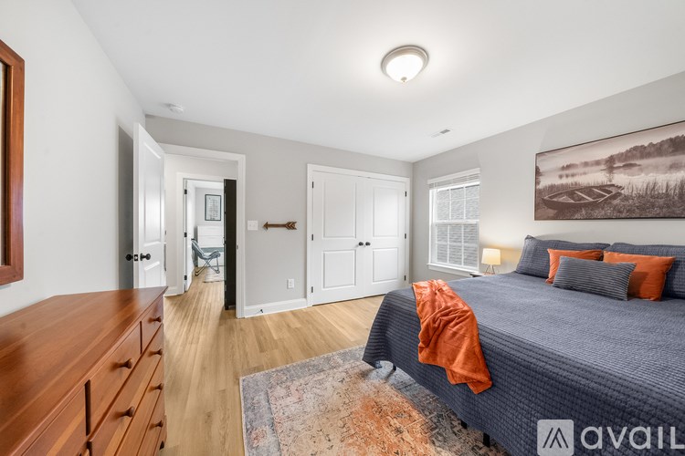 A bedroom with a bed, a dresser, and a painting on the wall.