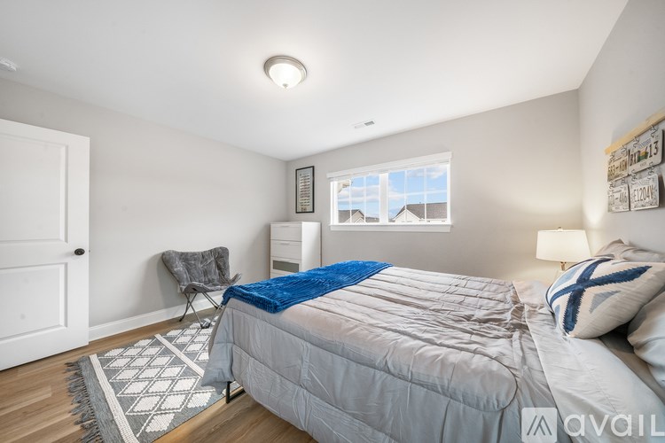A bedroom with a bed, chair, and window.