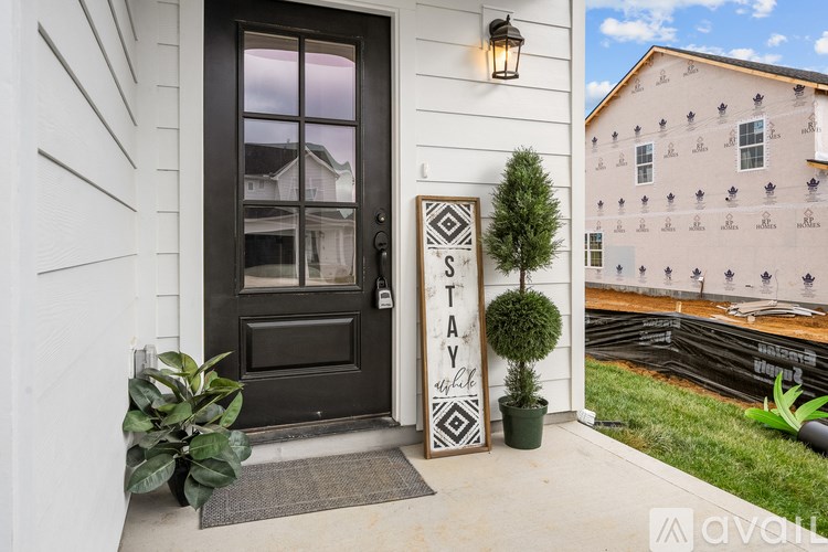 A black door with a sign that says "STAY" in front of a white house.