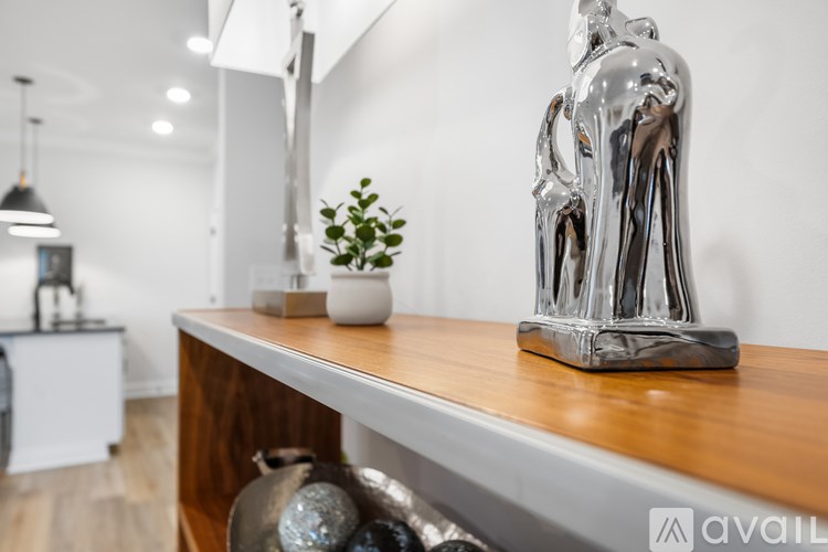 A silver sculpture of a horse is on a wooden shelf.