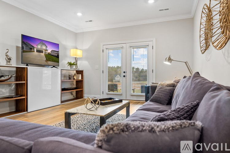 A modern living room with a grey sofa and a flat screen TV mounted on the wall.