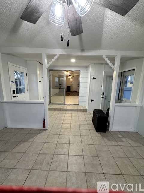 A spacious room with a white ceiling fan and tiled floor.