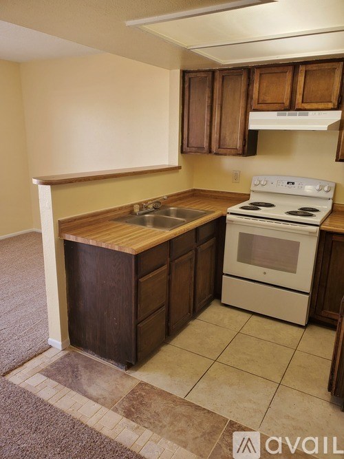 A kitchen with a white stove and wooden cabinets.