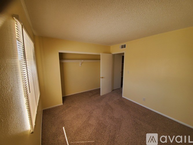 A room with a carpeted floor and a window with blinds.