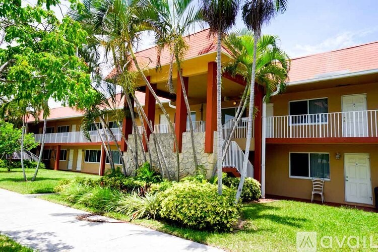 A building with a red roof and a balcony is surrounded by greenery.