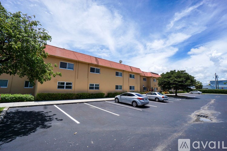 A parking lot in front of a building with a car parked.