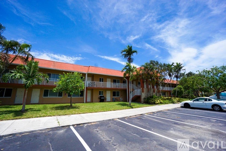A car is parked in a parking lot in front of a building with a red roof.