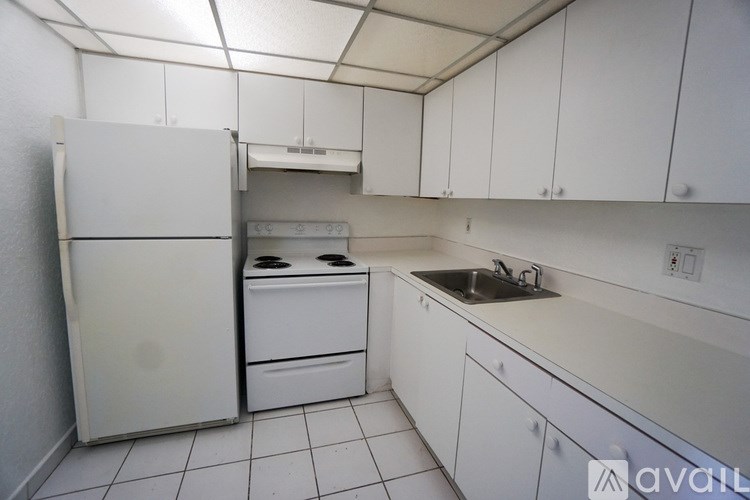 A white kitchen with a refrigerator, oven, and sink.
