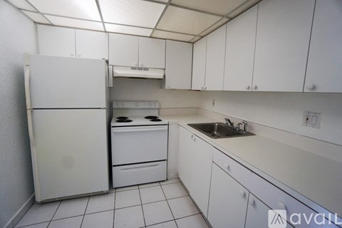 A white kitchen with a refrigerator, oven, and sink.