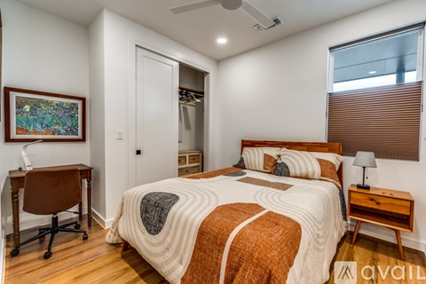 A bedroom with a bed, desk, and chair.