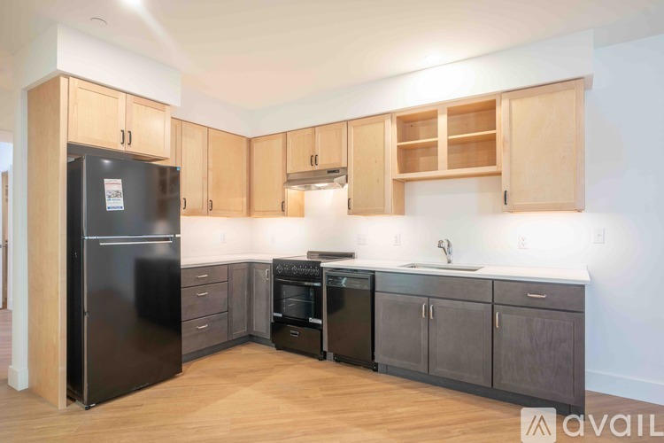 A kitchen with wooden cabinets and a black fridge.