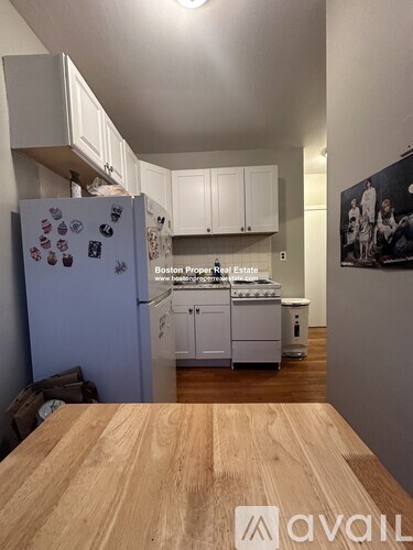 A kitchen with a refrigerator covered in magnets and a wooden table in the foreground.