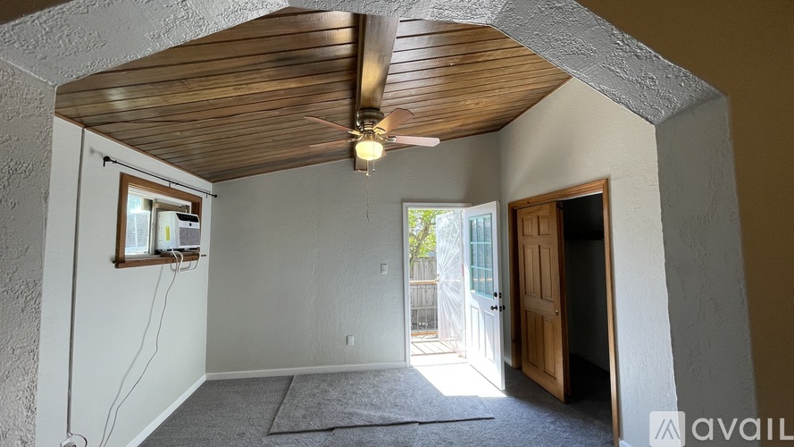 A room with a wooden ceiling and a window on the left wall.