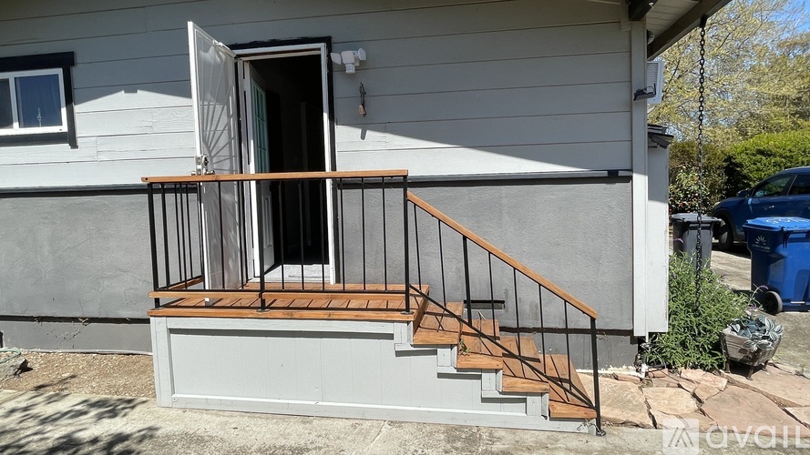 A house with a grey exterior and a wooden staircase leading to a door.