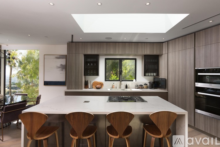A modern kitchen with a large island and wooden chairs.