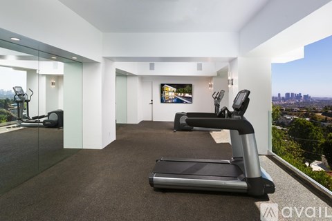 A spacious room with a treadmill and a television.