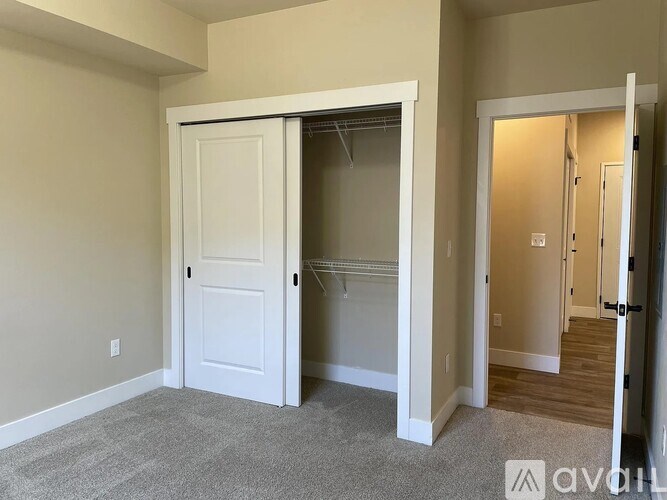 A room with a white door and a carpeted floor.