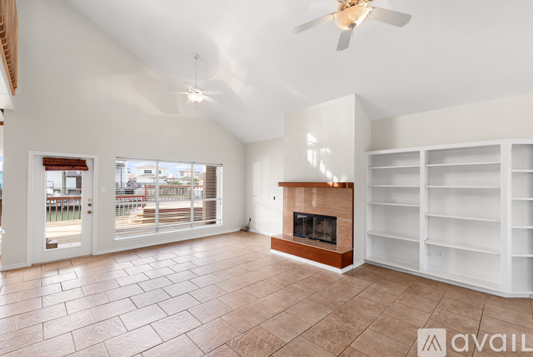 A spacious living room with a fireplace and a fan.