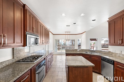 A kitchen with brown cabinets and granite countertops.