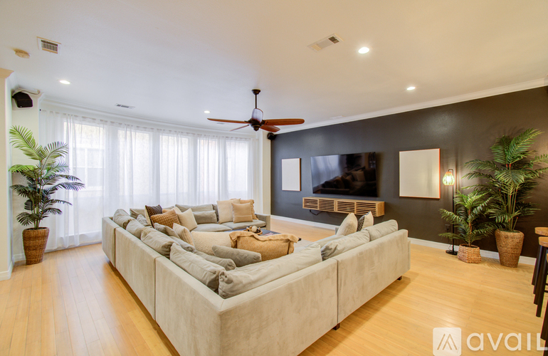 A living room with a large couch and a flat screen TV mounted on the wall.