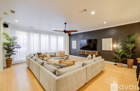 A living room with a large couch and a flat screen TV mounted on the wall.