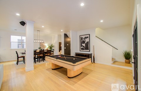 A billiard table is in the middle of a spacious room with a dining table and chairs.