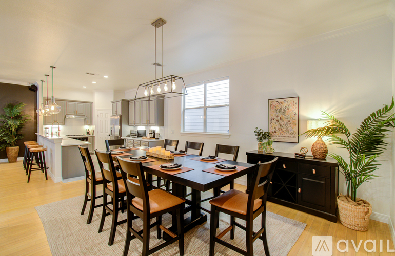 A dining room with a table set for six and a kitchen area in the background.