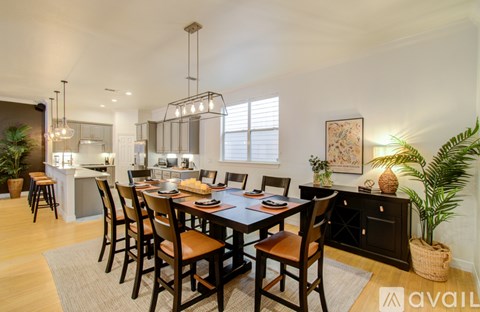 A dining room with a table set for six and a kitchen area in the background.