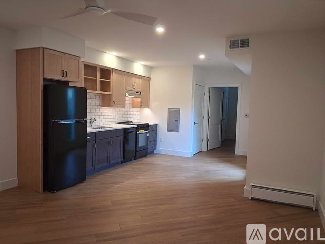 A kitchen with wooden cabinets and a black fridge.