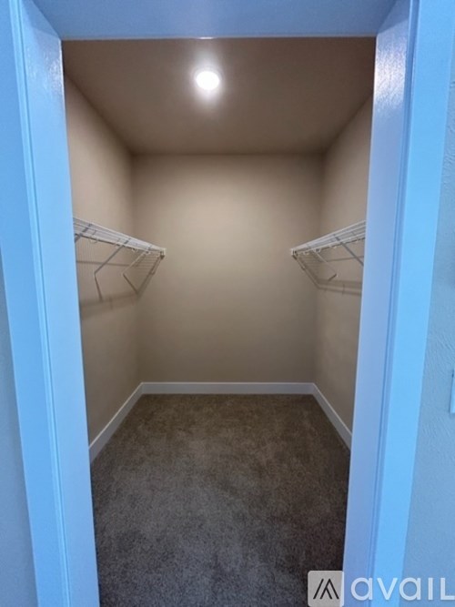 A small, empty room with a carpeted floor and two shelves on the wall.