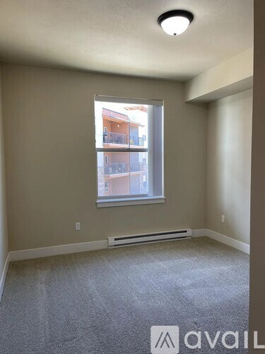 A room with a window and a carpeted floor.