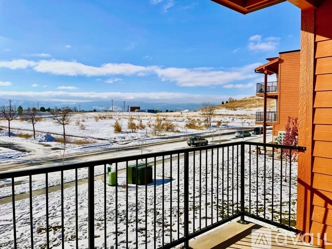 A balcony with a black railing overlooks a snowy landscape.