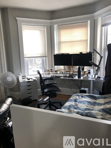 A room with a bed, desk, and computer setup.