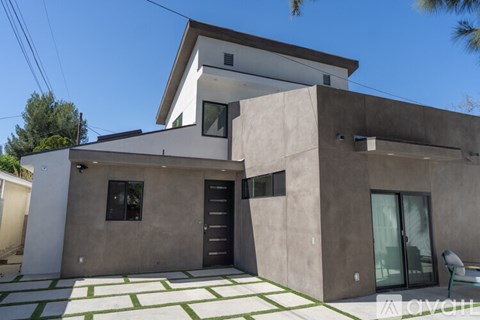 A modern house with a flat roof and a combination of grey and white exterior.