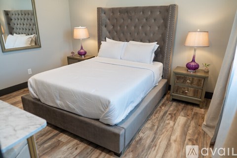A bedroom with a large bed and two purple lamps.