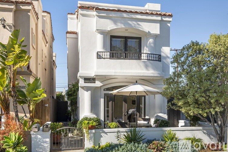 A white two-story house with a balcony and a patio.
