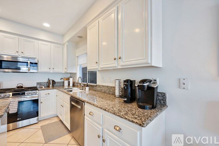 A kitchen with white cabinets and granite countertops.