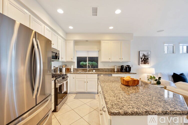 A modern kitchen with a granite countertop and stainless steel appliances.