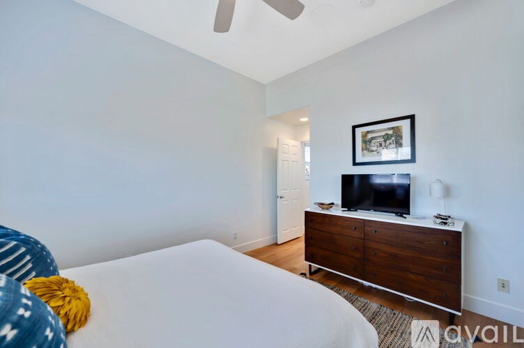 A bedroom with a bed, a dresser, and a television.